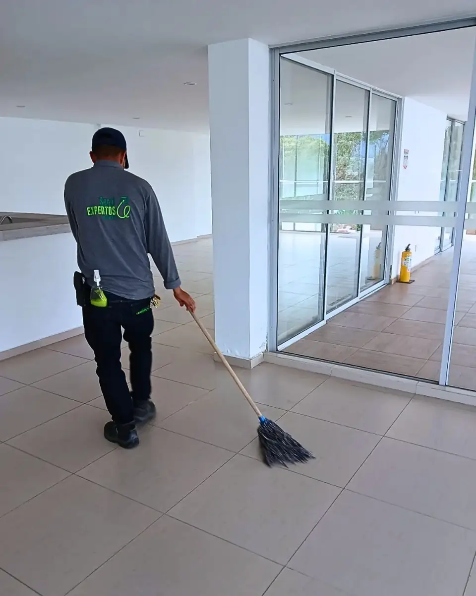 Auxiliar de aseo trapeando un lobby