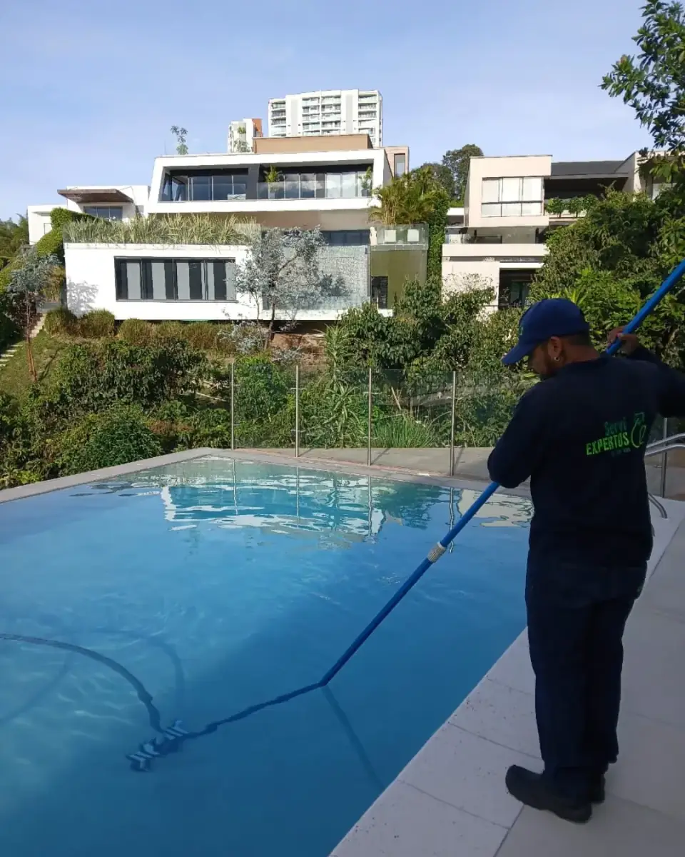 Piscinero limpiando la superficie de una piscina