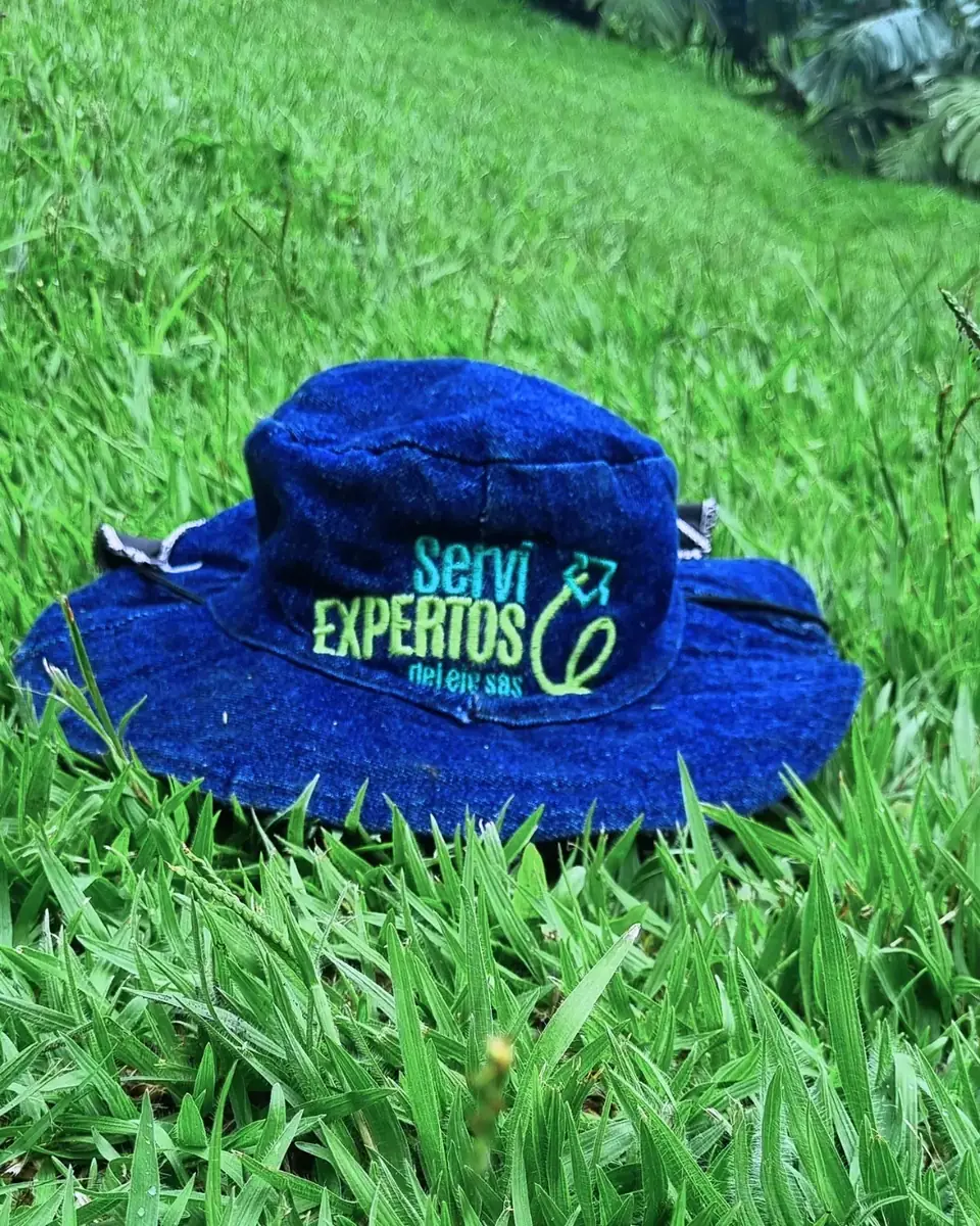 Sombrero con el logo de Servi Expertos sobre el pasto